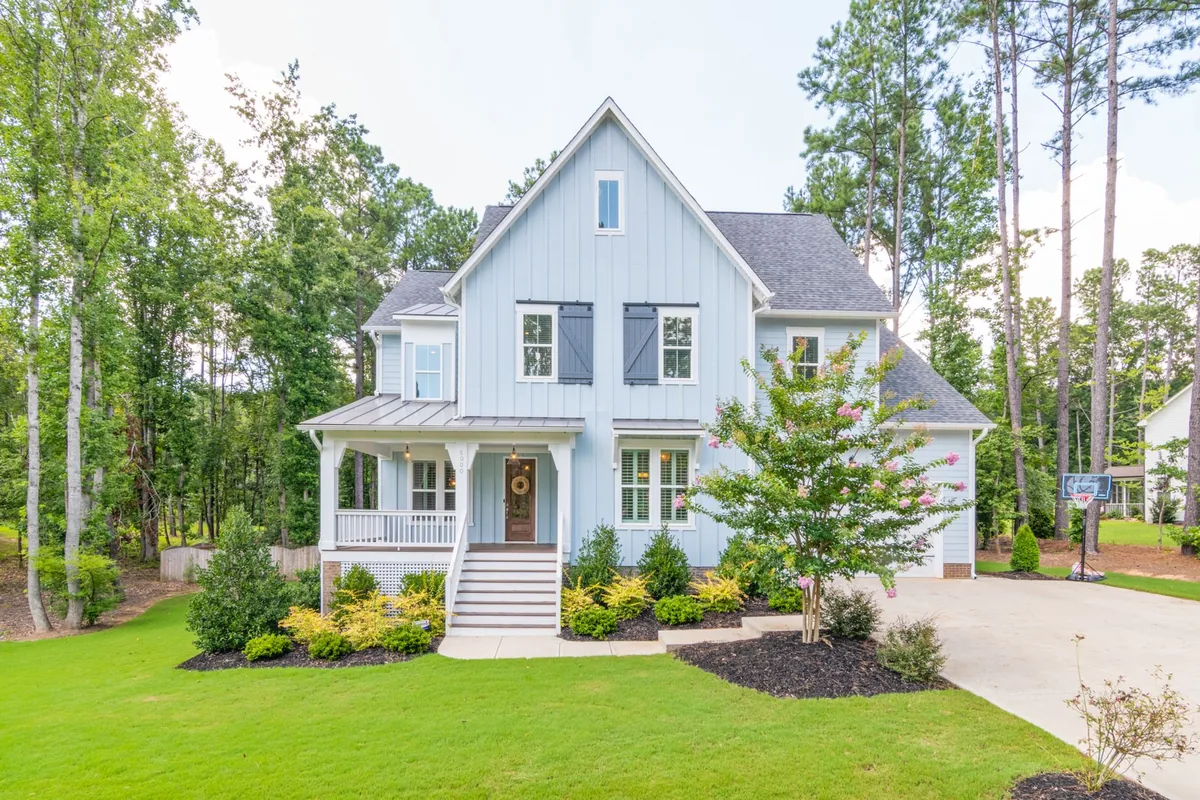 A suburban home surrounded by trees and a well-maintained lawn.