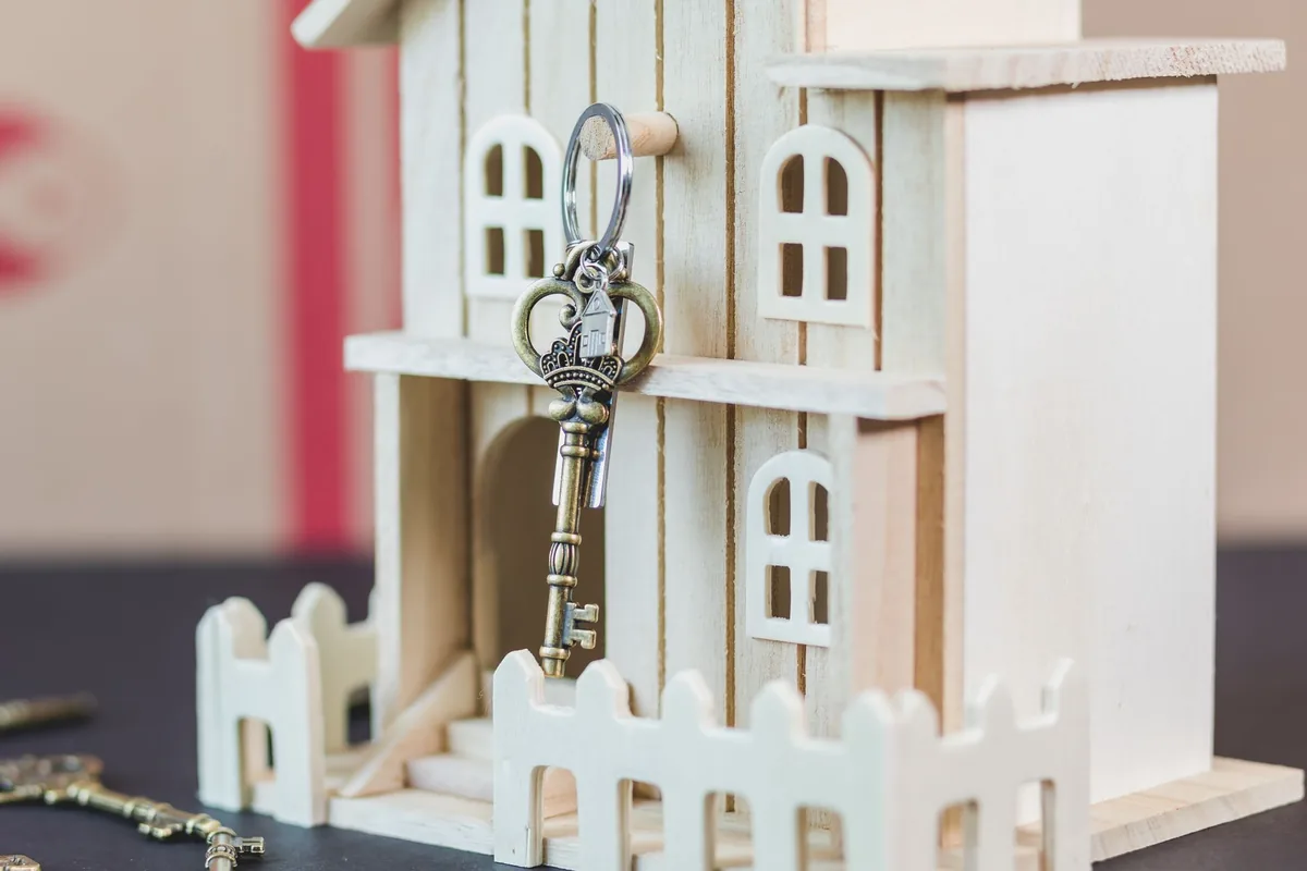 Small wooden model house with a vintage house key hanging on it