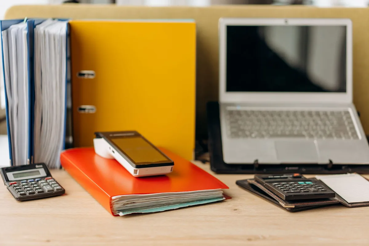 Desk with document binders, a laptop and two calculators for comparing home sale offers