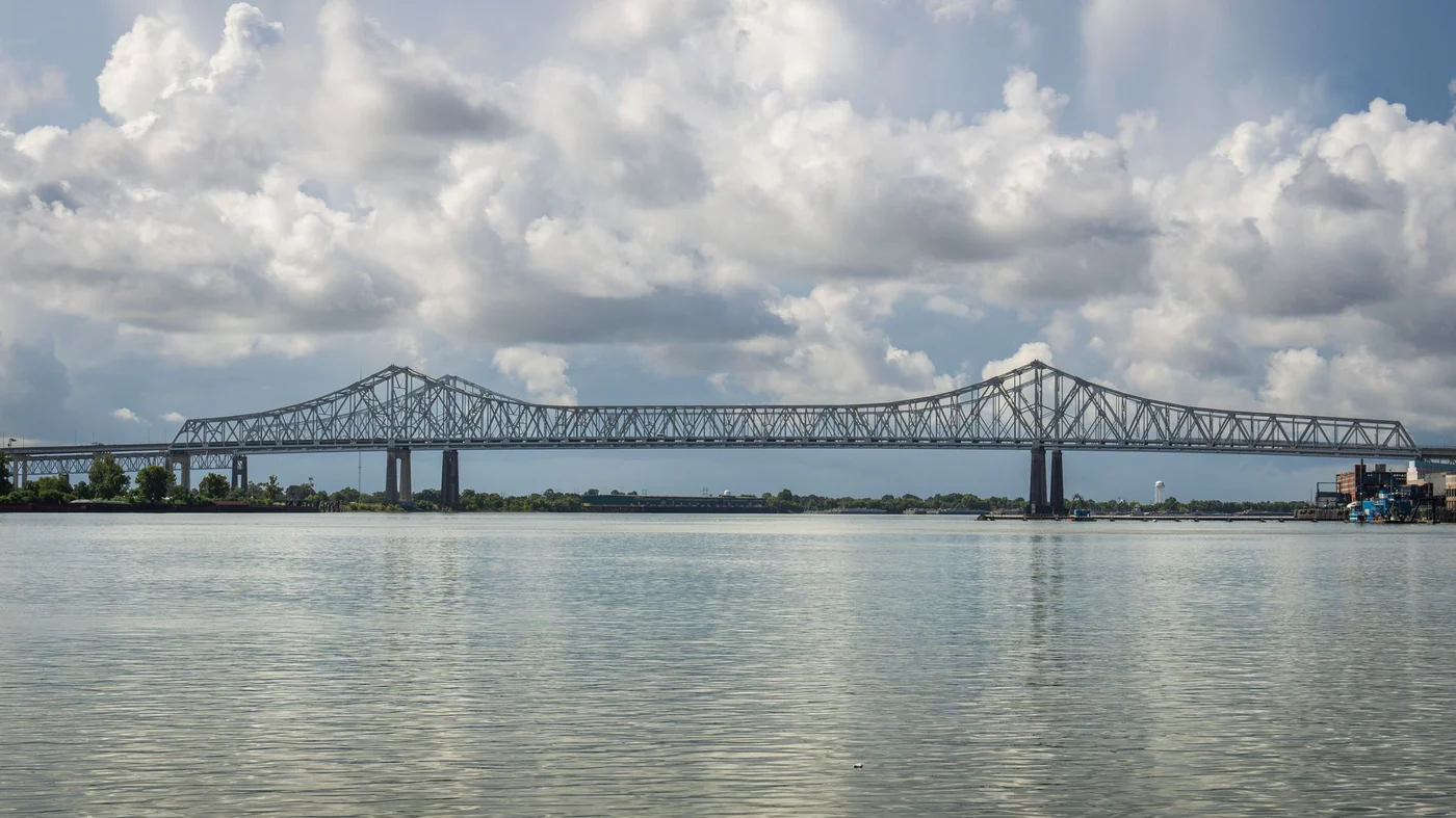 A long steel cantilever bridge crossing the Mississippi River in Louisiana under high summer cloud