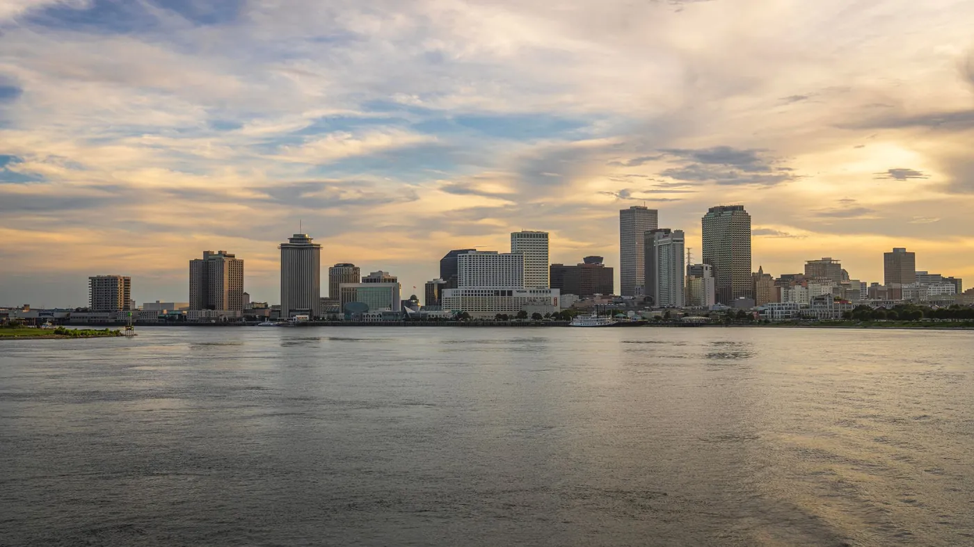 The New Orleans skyline seen across the Mississippi River at sunset, with a riverboat moored at the levee