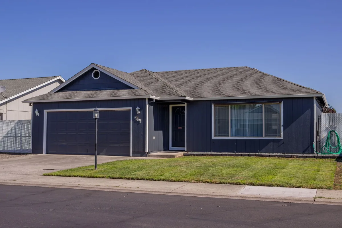Suburban house with driveway, garage, and well-maintained lawn.