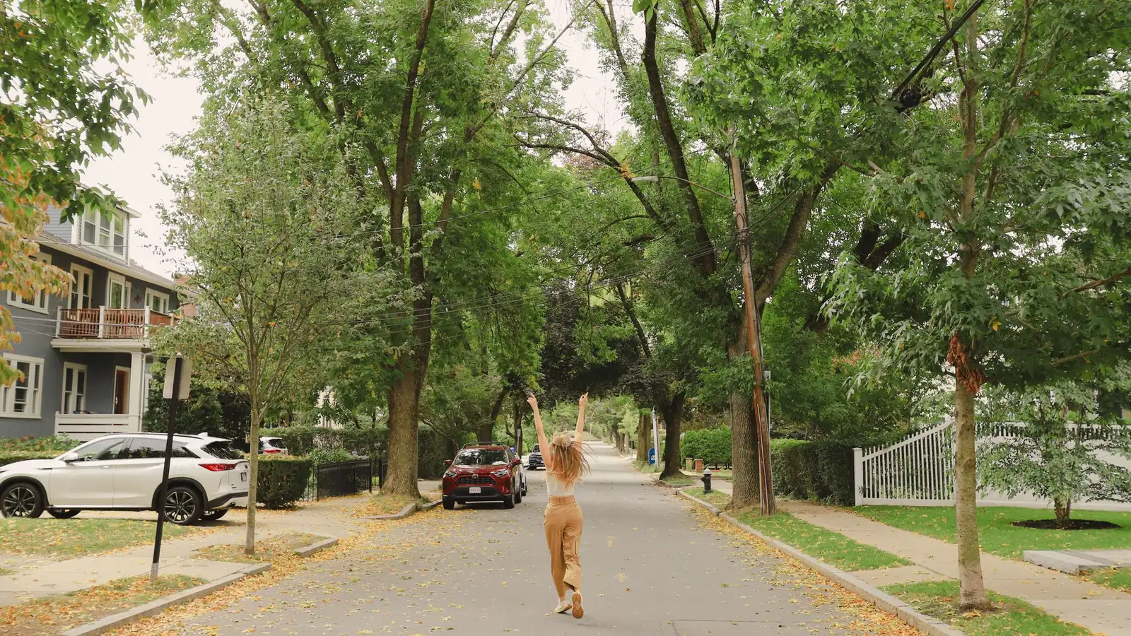 Tree-lined Boston residential street with a three-decker house and parked cars
