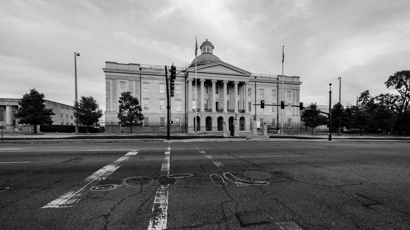 The Old Capitol in Jackson, Mississippi, a columned nineteenth-century stone building with a dome, seen in black and white from across an empty State Street