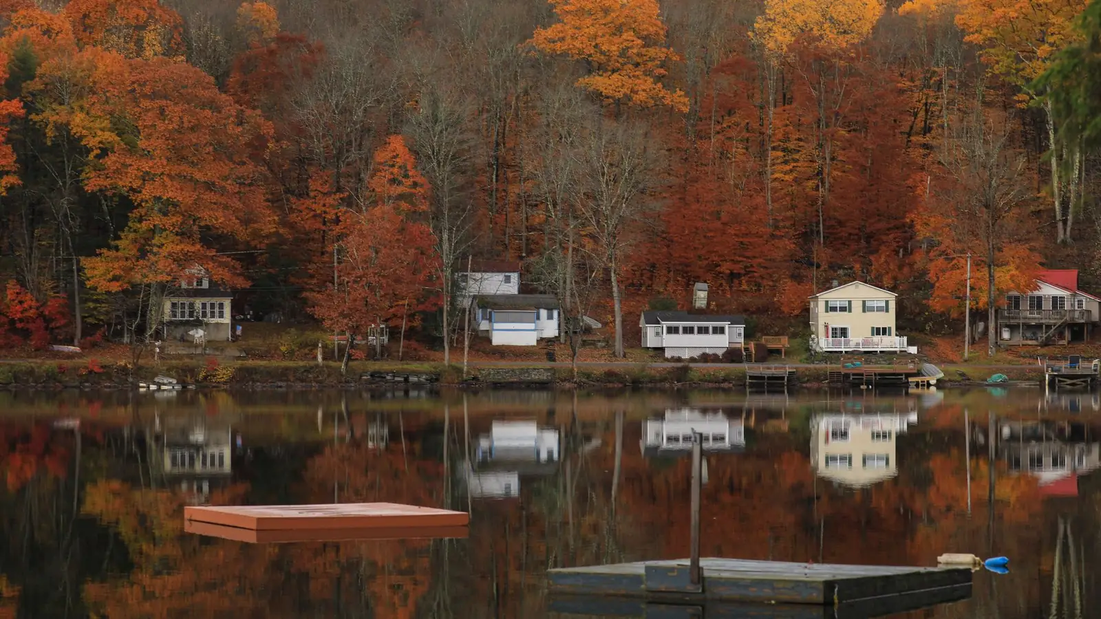 Houses along a lake shore in Catskill, New York, surrounded by autumn foliage