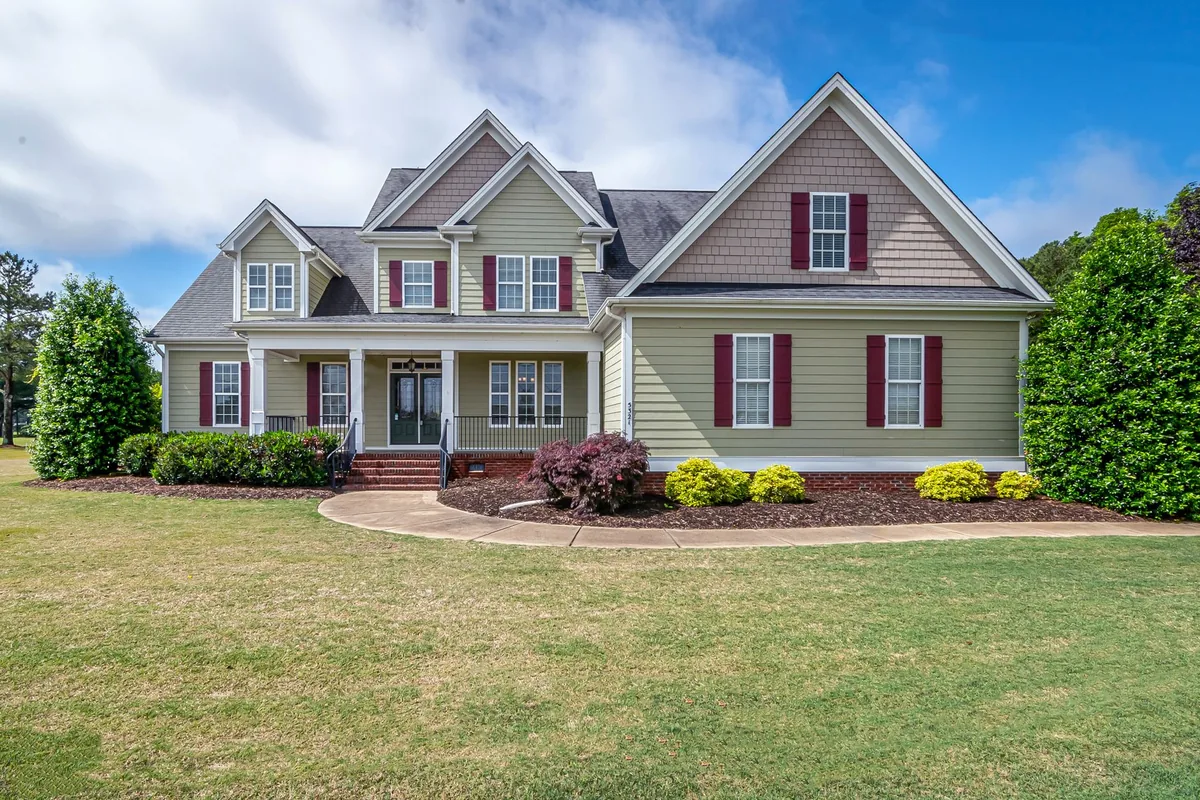 Two-story suburban house with manicured lawn and front porch.