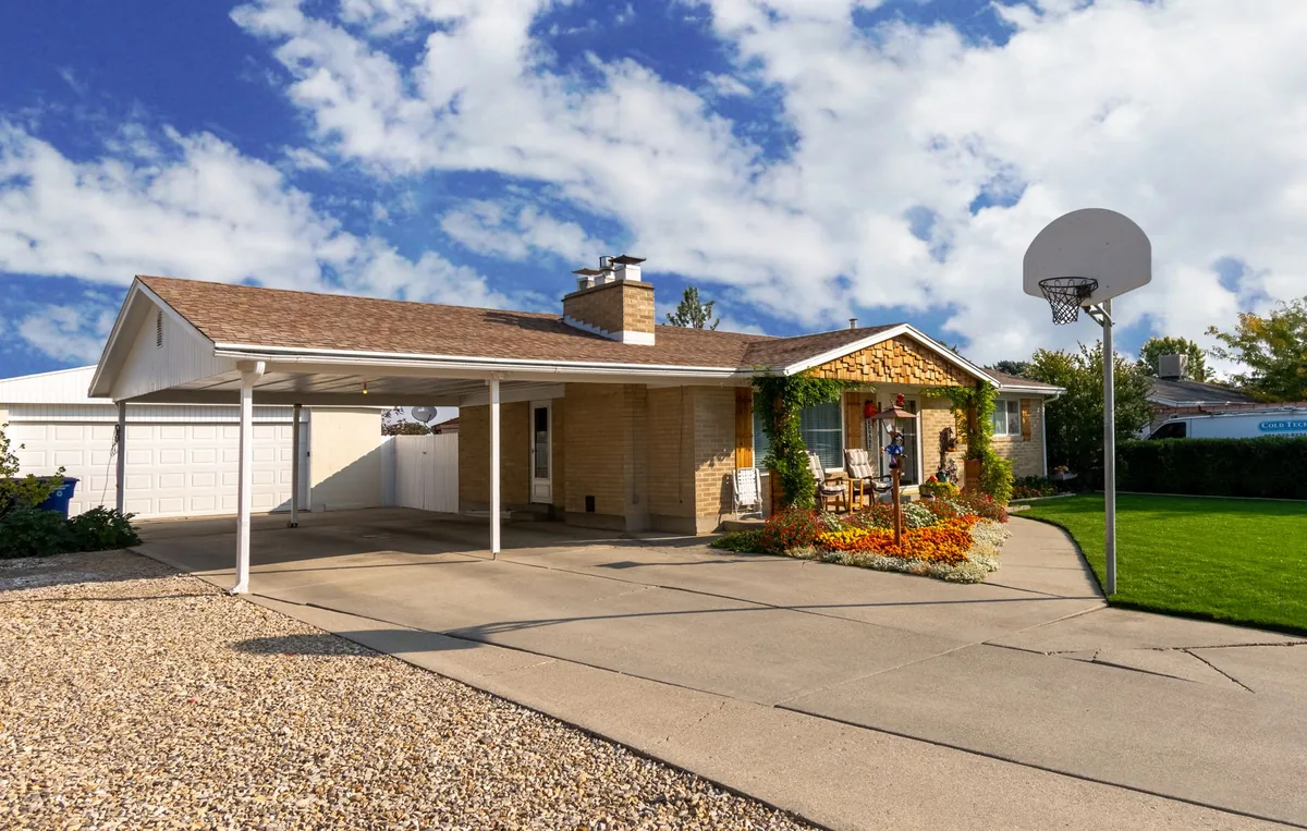 Suburban home with a basketball hoop, garage, and garden under a clear sky.