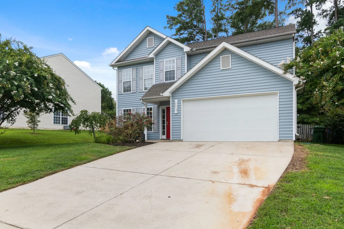 Two-story suburban house with spacious driveway and greenery.