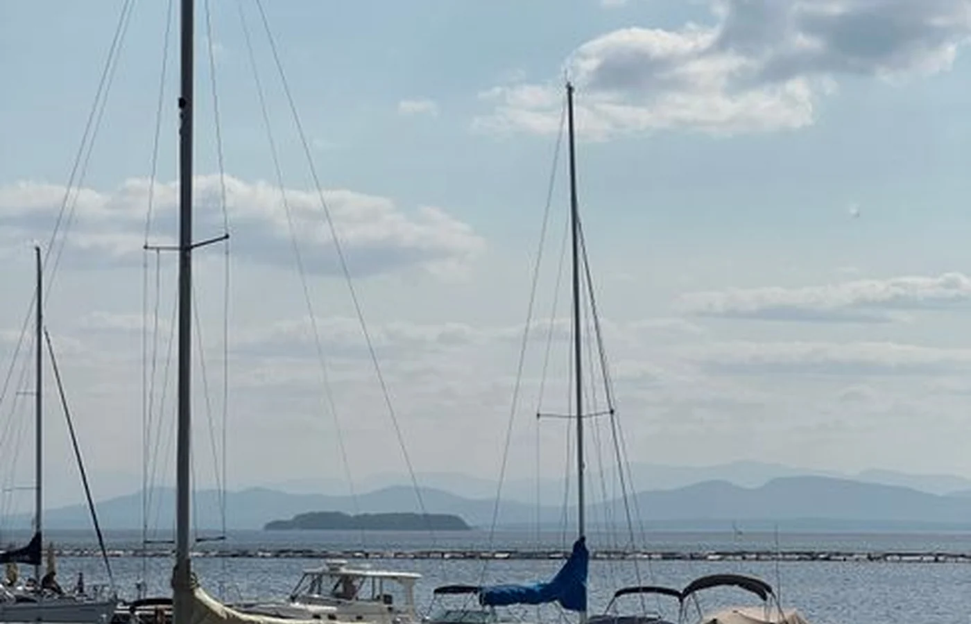 Sailboats moored in Burlington Harbor on Lake Champlain under a clear blue sky, with the far shore low on the horizon