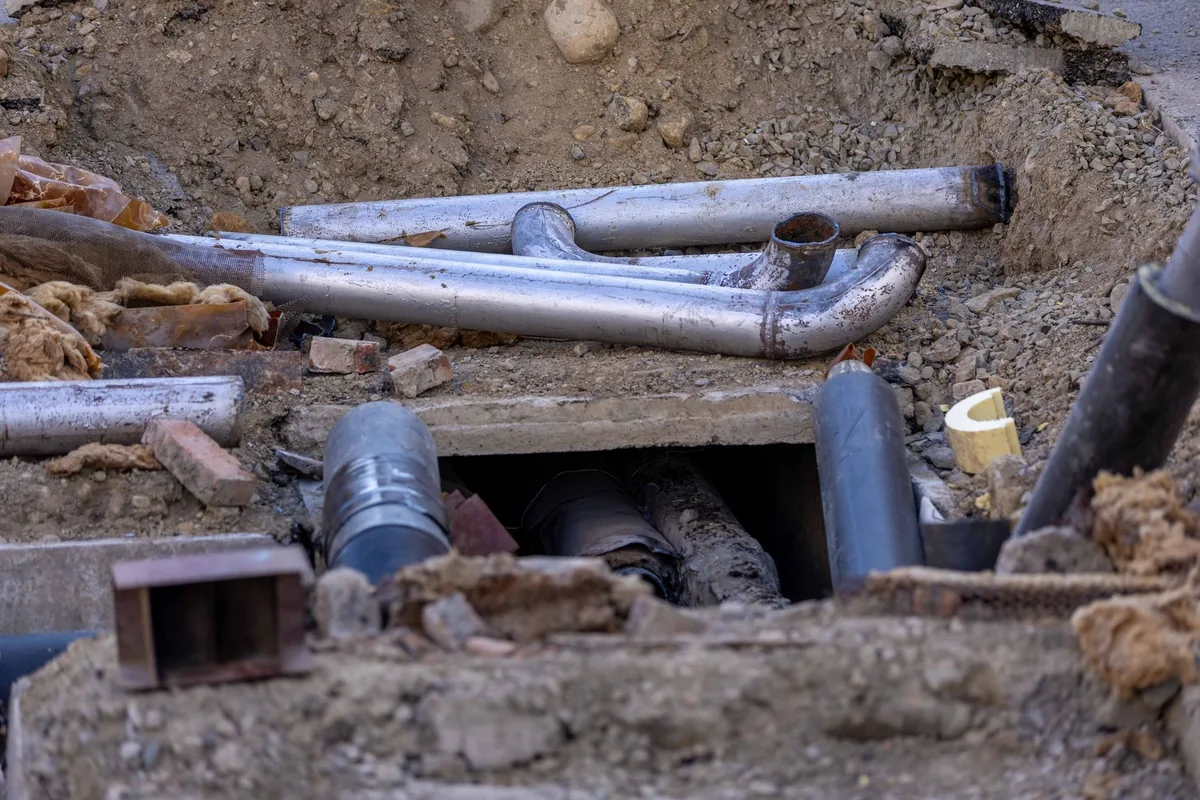 Metal and plastic pipes laid in an open excavated trench at a construction site