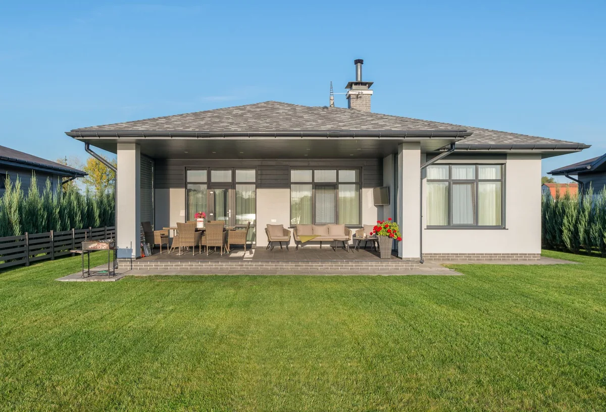 Single-story house with a covered patio and a large, evenly mowed green lawn