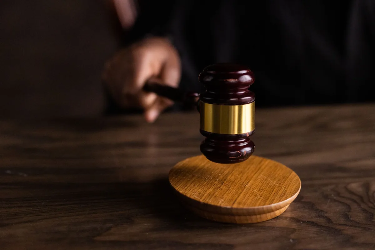 Wooden gavel above a round sound block on a dark wooden desk